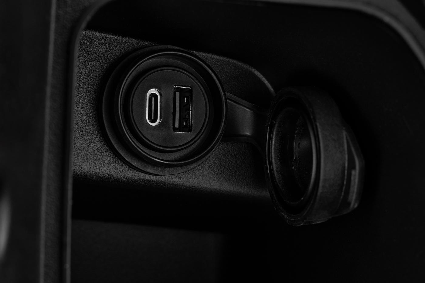 QJMOTOR MTX 125: Nahaufnahme der mit einer runden Schutzkappe versehenen USB-Anschlussstelle.