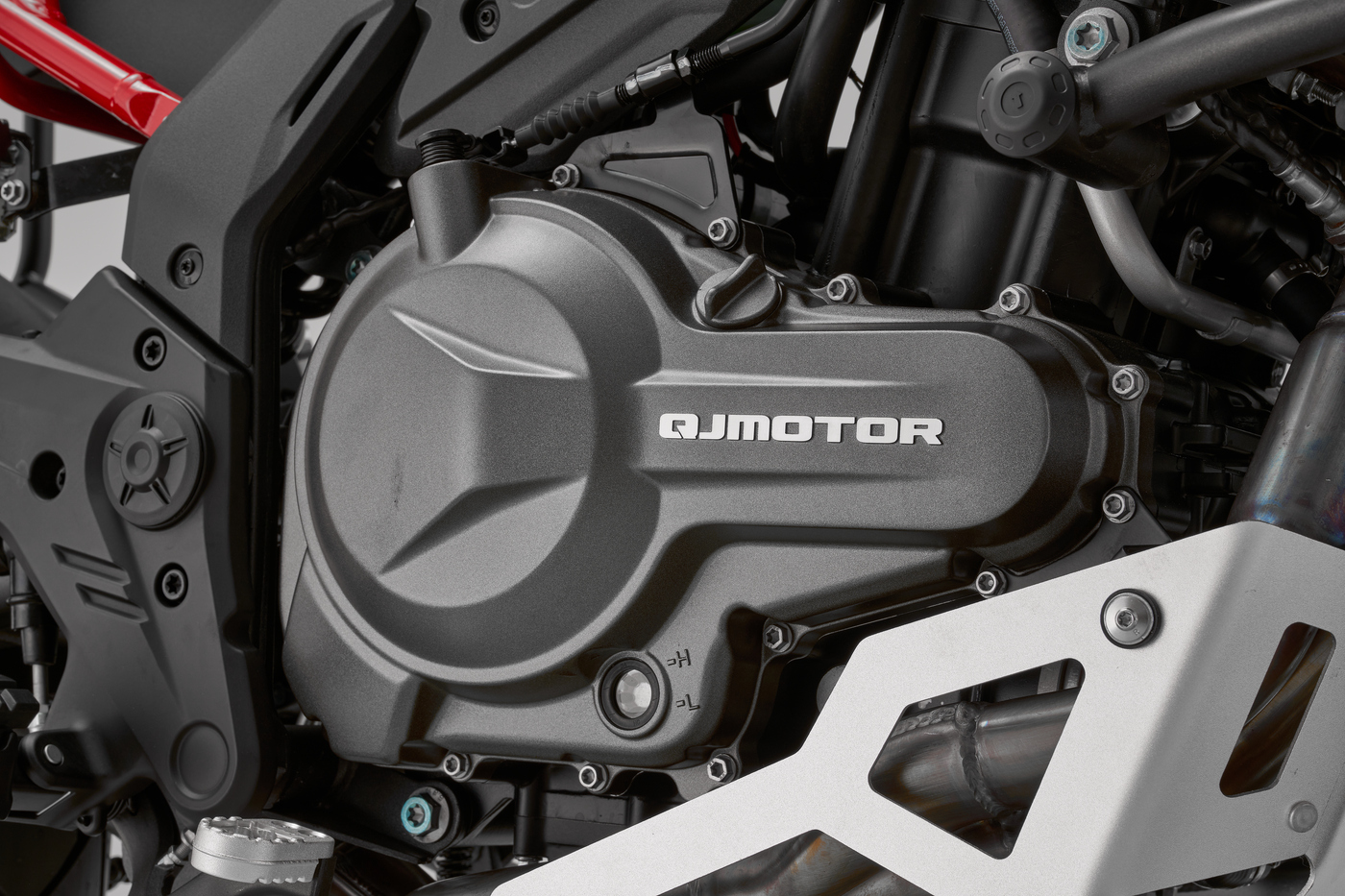 QJMOTOR SRT 600 SX: Nahaufnahme des Motors mit Gehäuse, Rahmen und seitlichem Schutzbauteil.