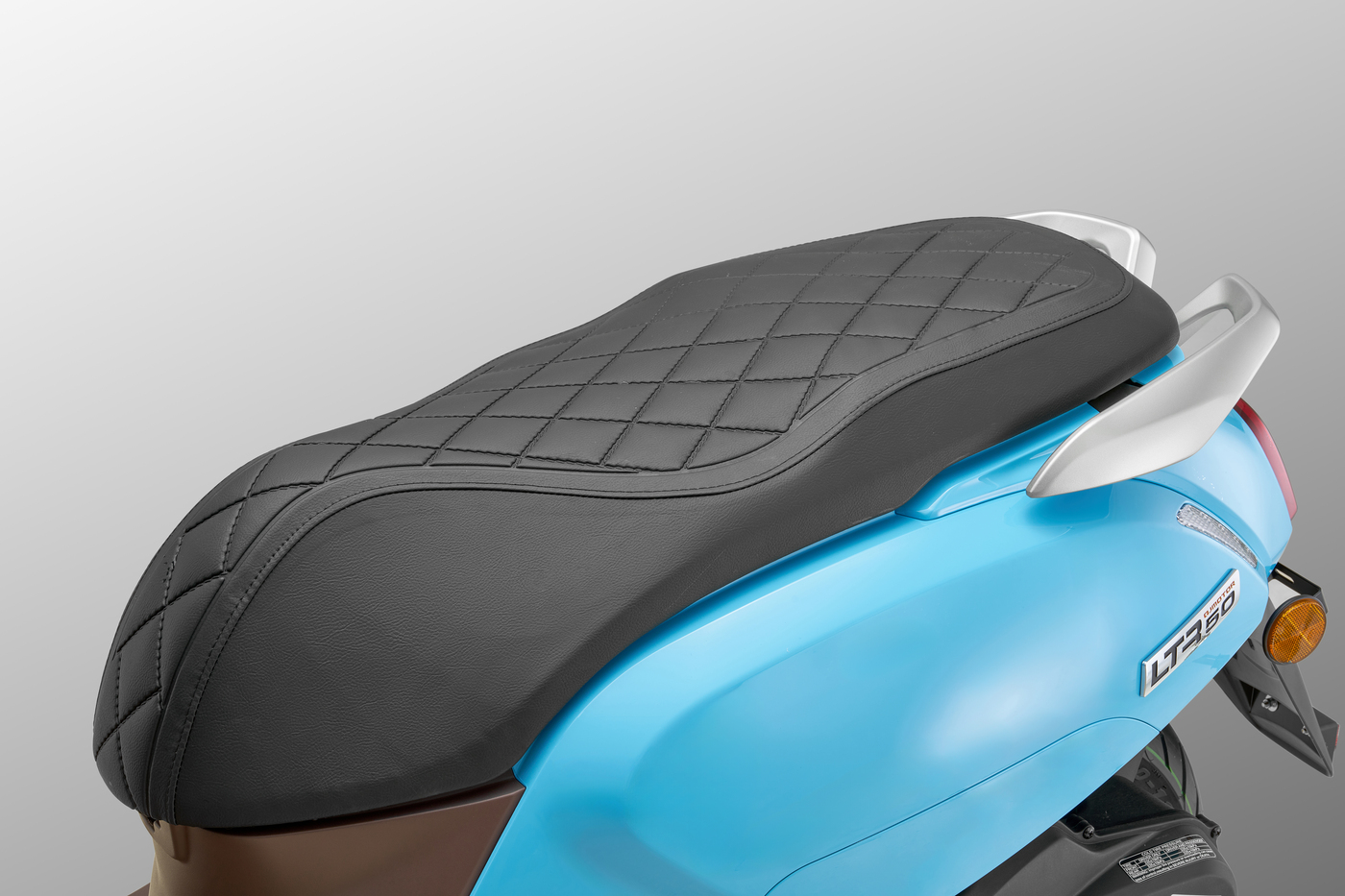 QJMOTOR LTR 50: Die gepolsterte schwarze Sitzbank mit Rautensteppung über der blauen Heckverkleidung.