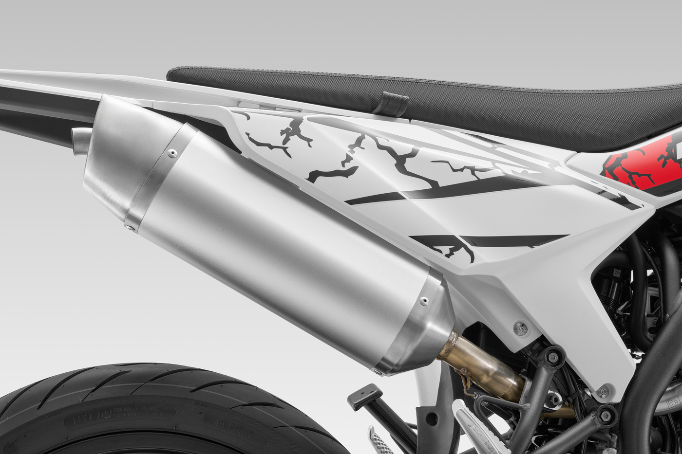QJMOTOR COV 125 SM: Der hoch montierte silberfarbene Auspuff neben der weiß-roten Heckverkleidung.